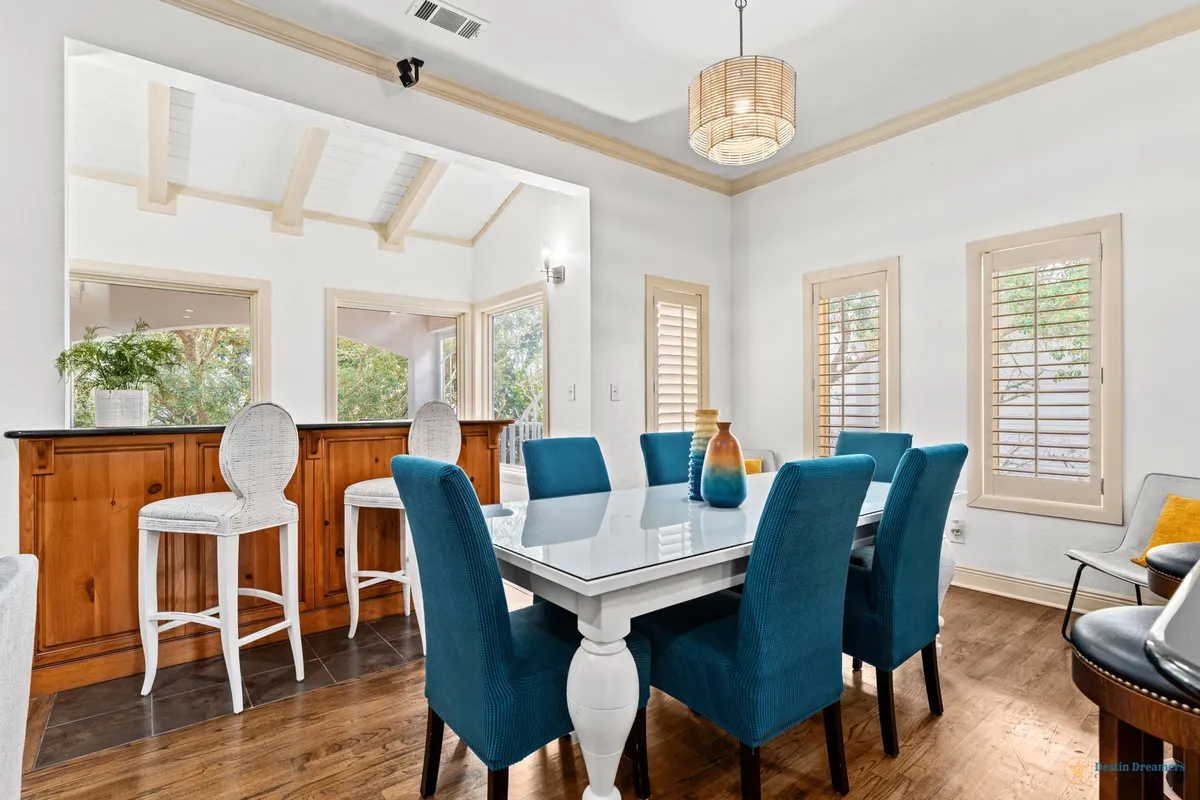 A vibrant dining area centered around a spacious table surrounded by blue chairs, with a bar area in the background. The setting feels bright, welcoming, and perfect for lively group gatherings or intimate dinners.